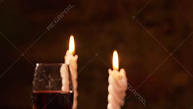 Person taking one of two glasses with red wine during romantic date