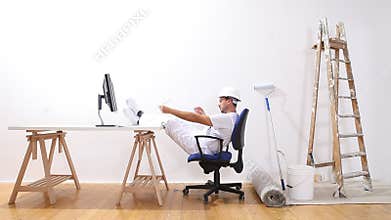 House painter man with a computer has finished work and relaxes, e-commerce and problems solved