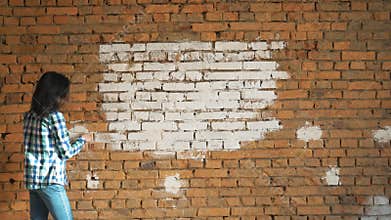 The woman paints a red brick in house in white color