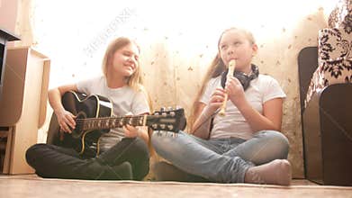 Two female teens playing musical instruments at home