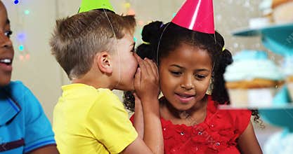 Boy whispering to girl while sitting with friends during birthday party 4k