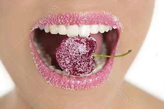 Cherry with sugra between woman teeth