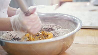 Baker in bakery mixes egg and flour