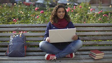 Biracial student in elevated mood sitting on bench, dreaming about bright future