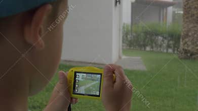 Child with camera making photos during rainy day