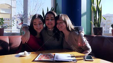 Friendly relationships, girls embrace and laughing in bright dining room