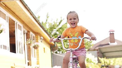 Happy child riding a bike. Girl on a bicycle. Сhildren summer activity.
