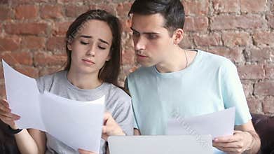 Young confused couple having problems with documents, searching help online