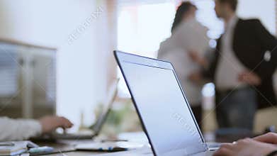 People working on laptops in meeting, two employees looking at papers, business