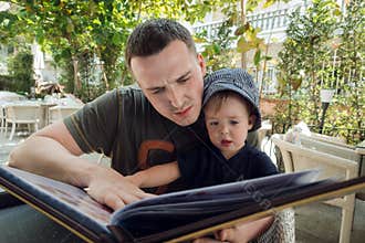 Man with boy exploring book on terrace