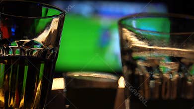 Blurred image of sport bar with TV and drinks in foreground