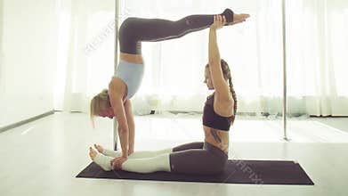 Two young women practicing acrobatic yoga.