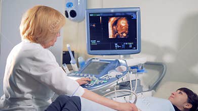 Gynecologist is carrying out an ultrasound procedure on a female patient