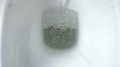 Close-up of yellow pee flushing down the toilet