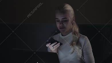 Girl using smart phone voice recognition, dictates thoughts, voice dialing message at night evening home student model