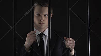 Angry man standing behind prison bars, official arrested on bribery charges