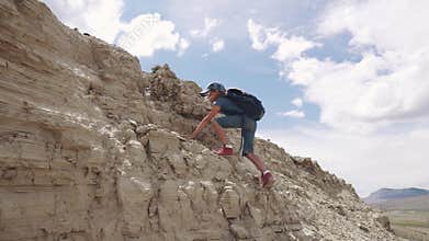 Child climbs the hill. a little girl traveler with backpack