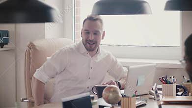 Handsome young CEO businessman talking, laughing at office meeting. Confident happy boss at his workplace slow motion.
