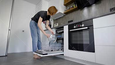 Happy Young Woman Arranging Plates In Dishwasher At Home