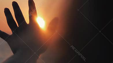 Female hand close-up in the sun at sunset. The sea sunset warms the female hand