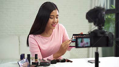 Beautiful woman use brush while review make up tutorial broadcast live video to social network by internet.