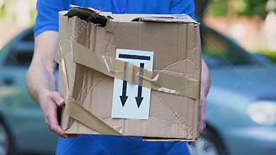 Frightened delivery worker giving broken customer parcel, shipment accident