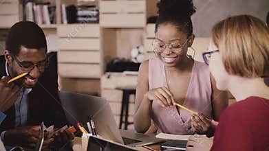 Cheerful African American female manager brainstorming with happy multiethnic colleagues in modern loft healthy office.