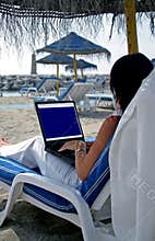 Business woman working on a laptop on the beach
