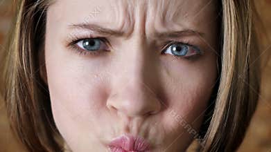Young attractive girl is winking, duck face, fool around, watching at camera, brick background