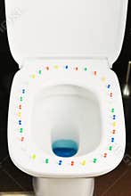 Conceptual image of a hemorrhoid disease with multi-colored thumbtacks on toilet bowl cover