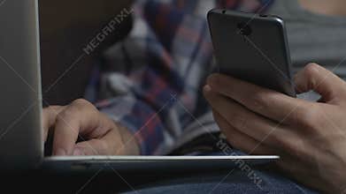 Man using phone online banking application and typing laptop, internet shopping