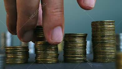 Man putting down coin on stacks of coins. Increase wealth and profit.