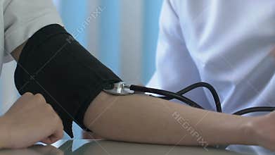 Doctor measuring boy blood pressure with stethoscope, draft checkup medical care