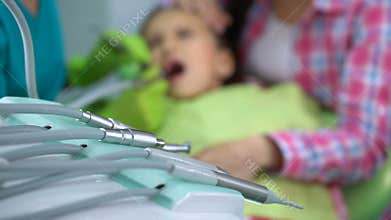 Little boy afraid of dental drill treatment, mother soothing child, background