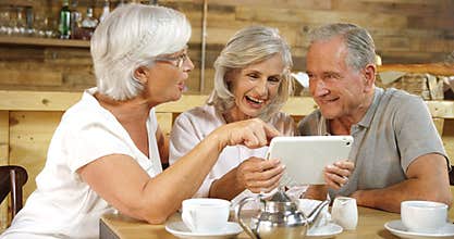 Senior friends discussing over the digital tablet in cafe 4k