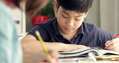 Cute asian teen boy doing your homework and looking a camera with smile face at home.