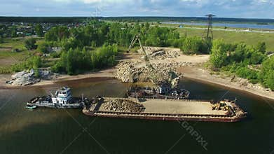 Dry cargo ship bulk carrier crane load crushed stones rock in river dock aerial view fly right
