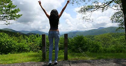 Wanderlust and travel concept with space for text. Woman traveler on the top of mountains, jumps and shows gesture of