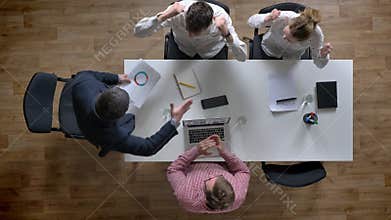 Director coming in and showing document, team of four people cheering and enjoying their victory, topshot, sitting in