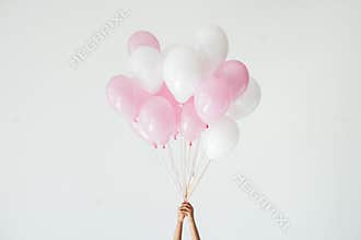 partial view of hands holding bunch of pink and white balloons
