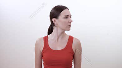 Portrait of a brunette woman turning the head left and right. Doing strengthening exercise for the neck.