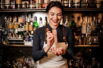 Smiling bartender girl breaking an ice cube