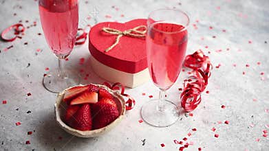Bottle of rose champagne, glasses with fresh strawberries and heart shaped gift