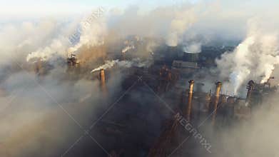 Aerial view. Pipes Throwing Smoke in the Sky. Large Plant on the Background of the City.