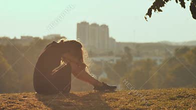 Sad girl silhouette sit alone in the grass so lonely and cry.