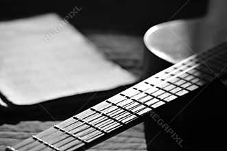 The guitar and music books illuminated by the sun. Black and white