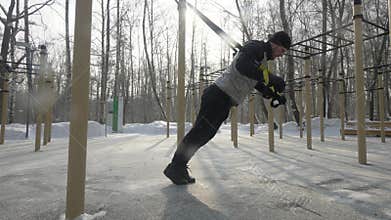 Man bodybuilder doing squat exercise on sports ground in winter park