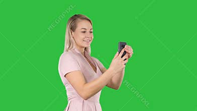 Beautiful young woman doing selfies on a green screen, chroma key.