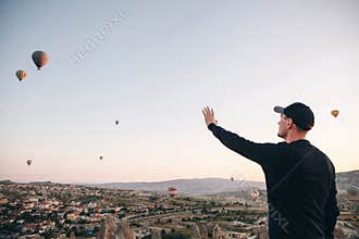 A man admires a beautiful view of the flying balloons.