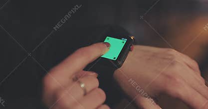 Woman using her smartwatch touchscreen wearable technology device. Green screen smartwatch. Young woman trying new smart
